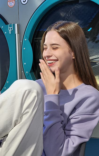 A woman laughing in a laundromat.