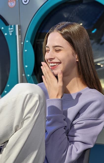 A woman laughing in a laundromat, taken in Portrait Mode with Blur effect applied.