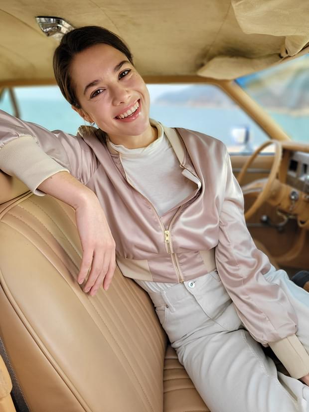 Woman sitting in the driver's seat, taken in Portrait Mode with Blur effect applied.