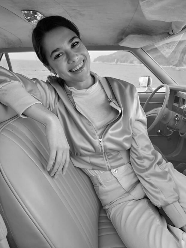 Woman sitting in the driver's seat, taken in Portrait Mode with High-key Mono effect applied.