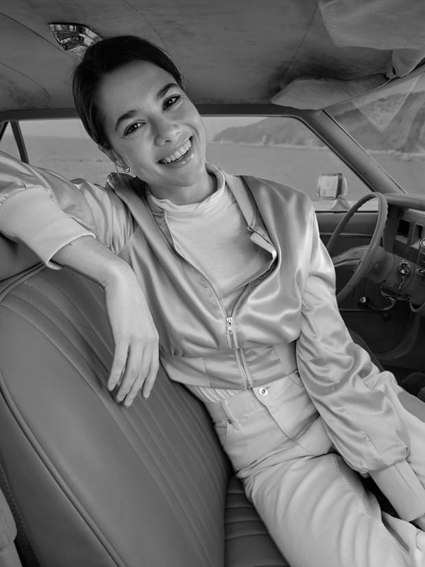 Woman sitting in the driver's seat, taken in Portrait Mode with Low-key Mono effect applied.