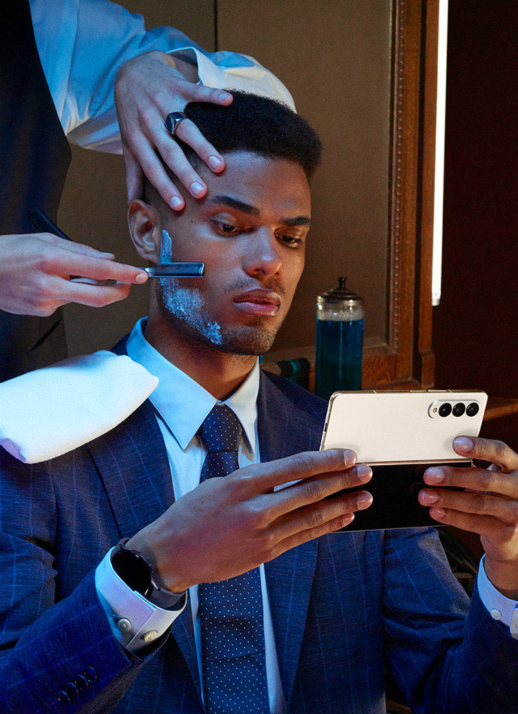 A man holds Galaxy Z Fold4, unfolded while sitting in a barber's chair.